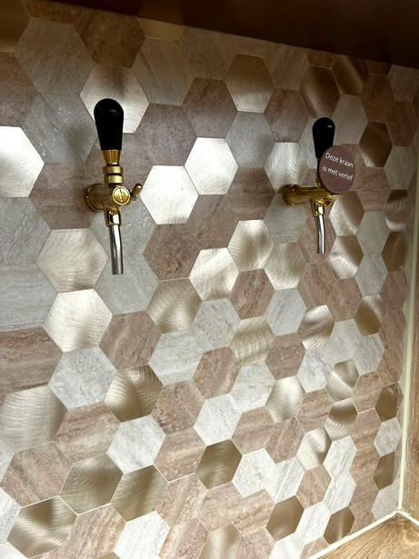 Detail van de tapkranen tegen de hexagon tegelwand